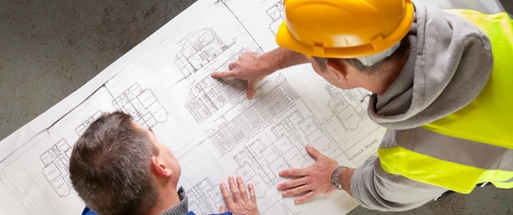 two construction workers carefully examining blueprints