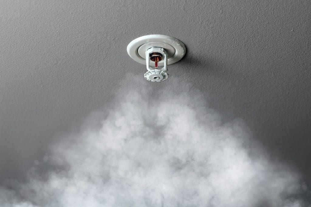 A Fire sprinkler with smoke rising toward it