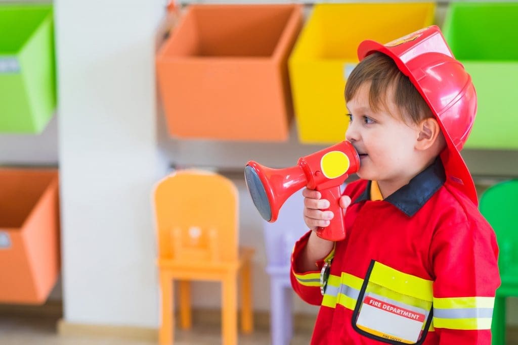 a child in a fireman costume using a megaphone