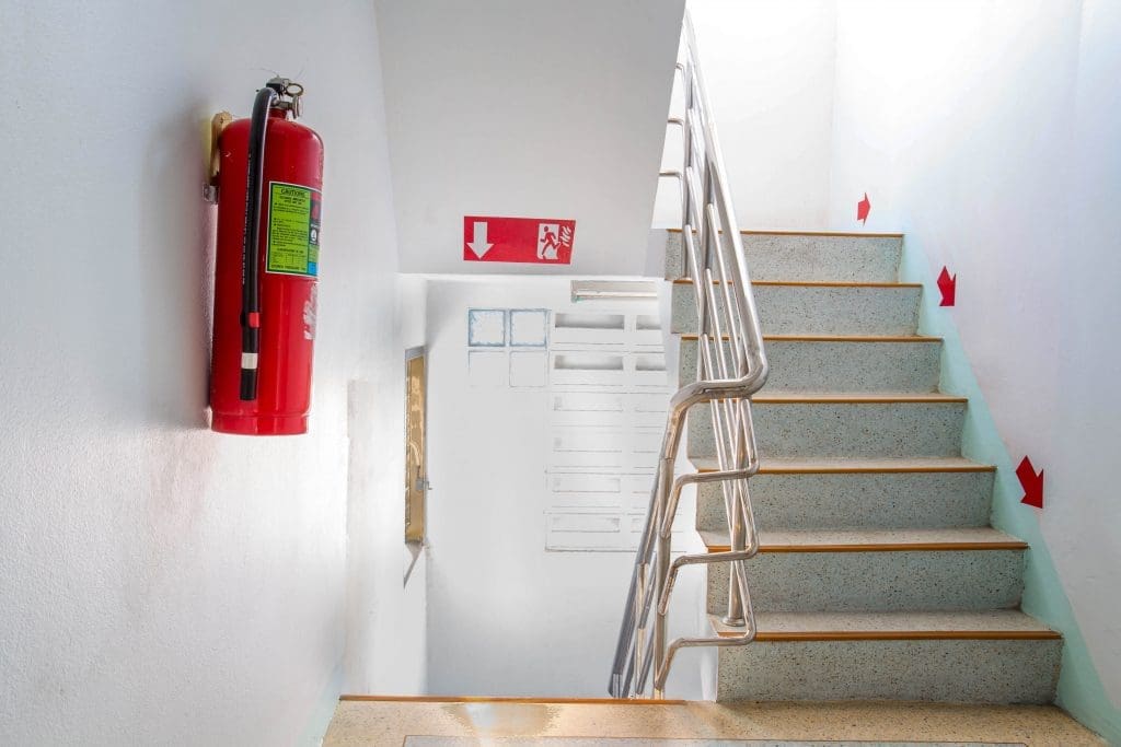 a residential building stairway floor with a fire extinguisher on the wall to the left of the image
