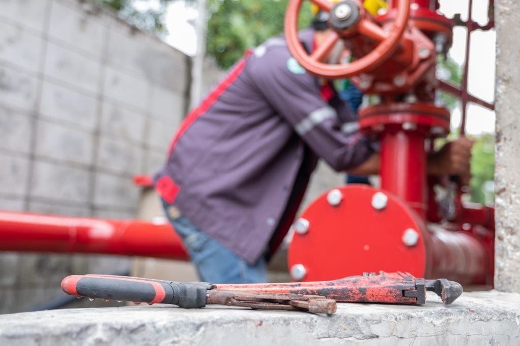 low angle image of a construction worker repairing a fire sprinkler